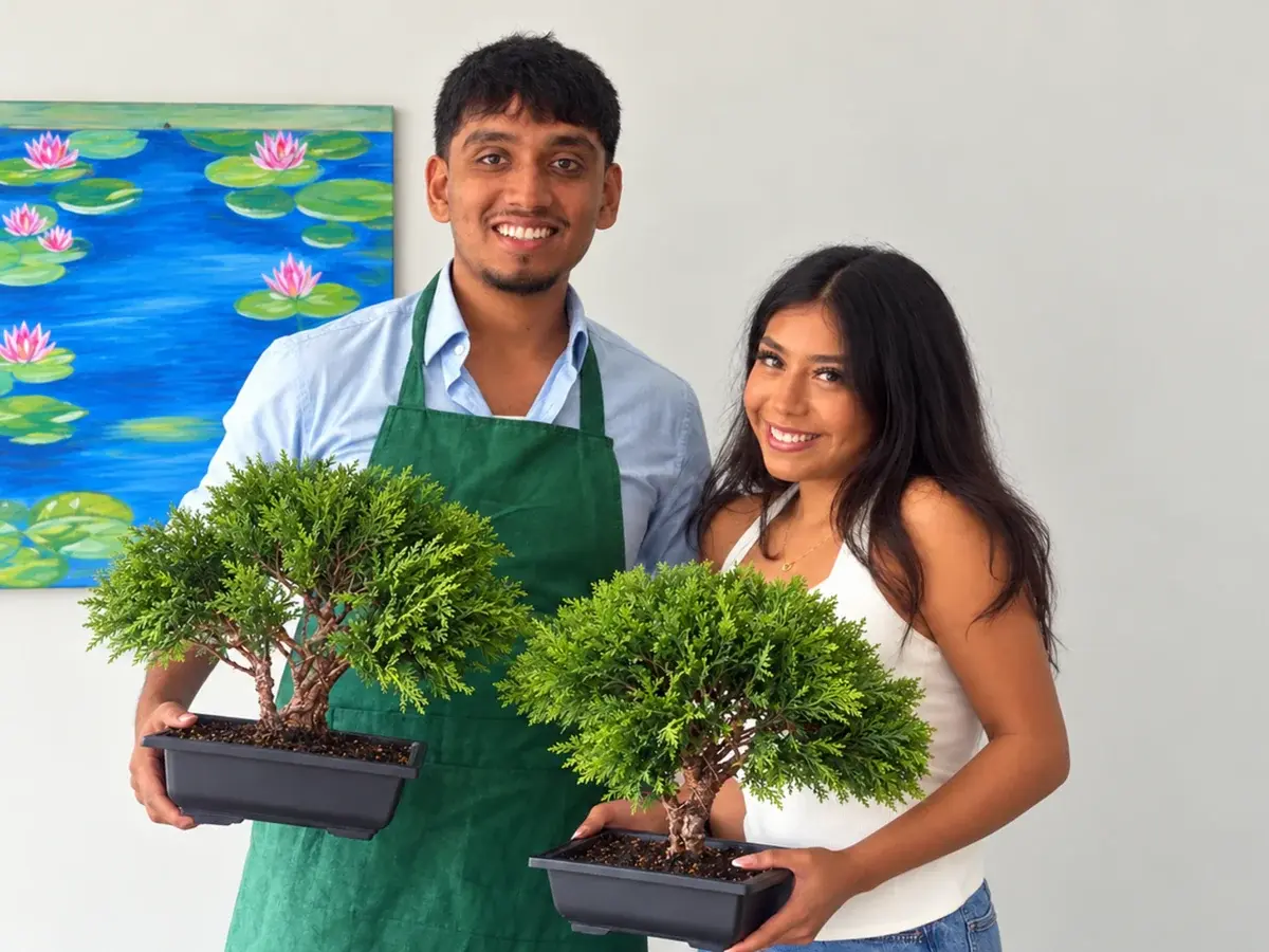 Two workshop guests holding their finished bonsai trees