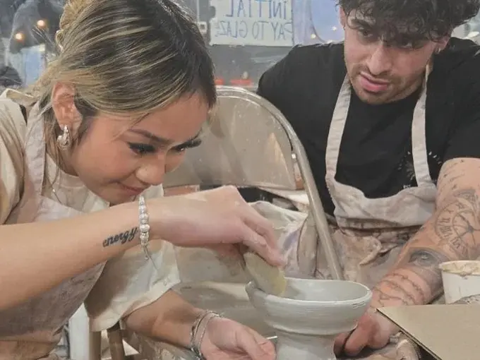 A couple working together on clay at a pottery wheel