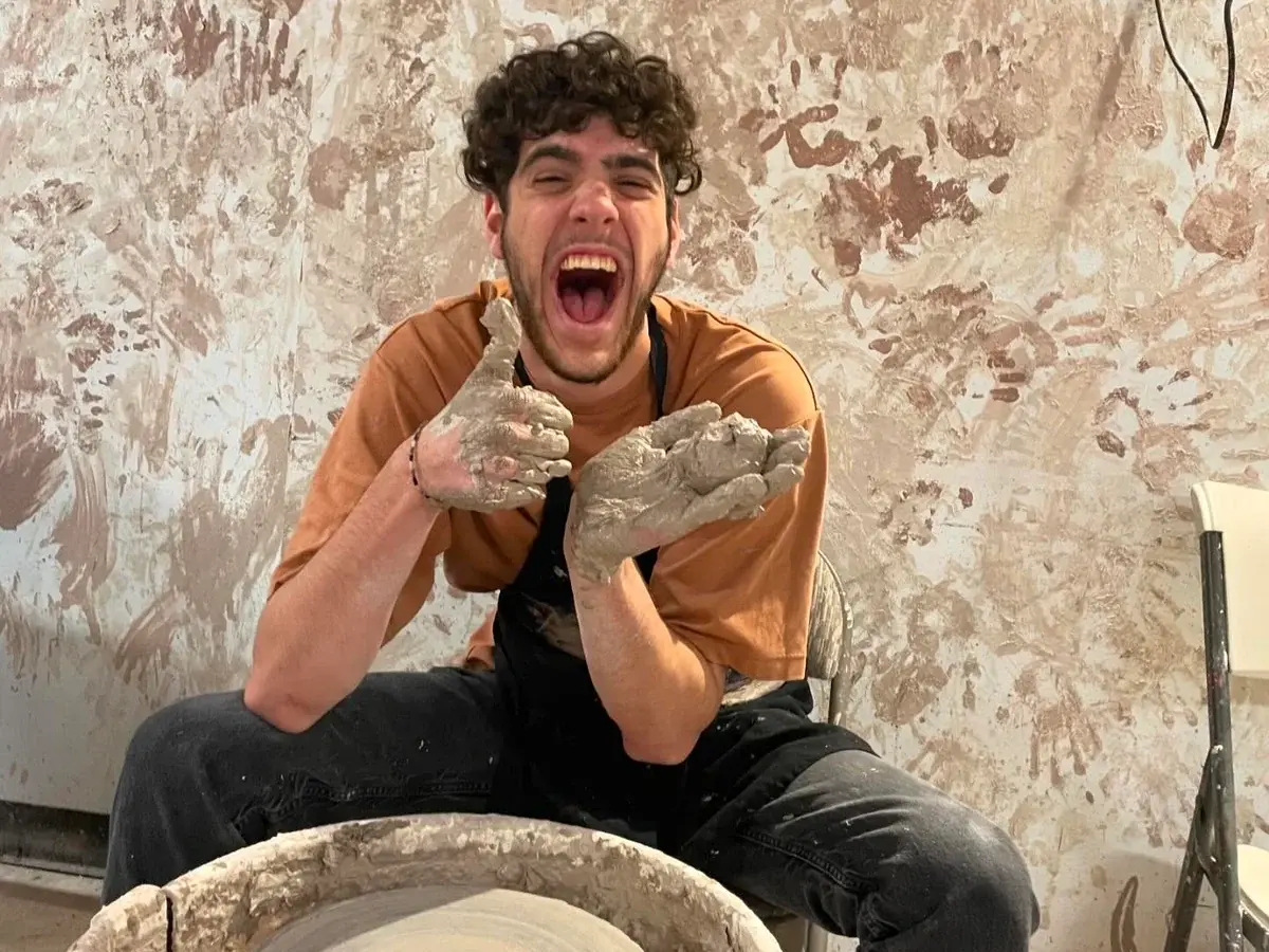 A smiling workshop guest holding a freshly made clay cup