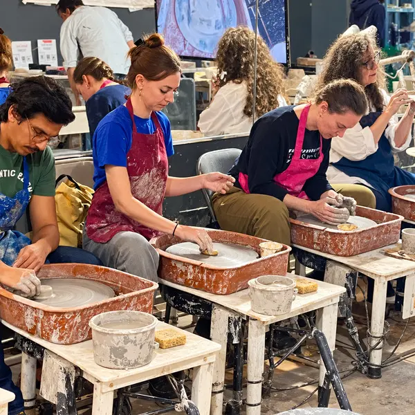 Students shaping clay on pottery wheels during a beginner workshop